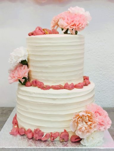 Pastel de dos pisos decorado con flores rosas y blancas.
